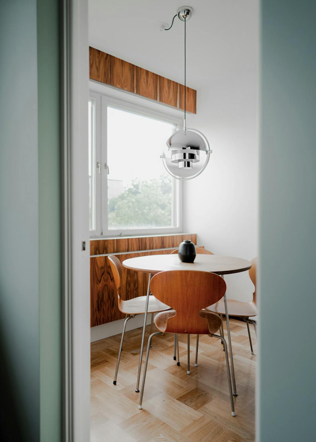 De eethoek is Arne Jacobsen ten top. Zowel de tafel als stoelen zijn originele ontwerpen en de wand is bekleed met echt palissander. Arne Jacobsen ronde eettafel en stoelen van hout