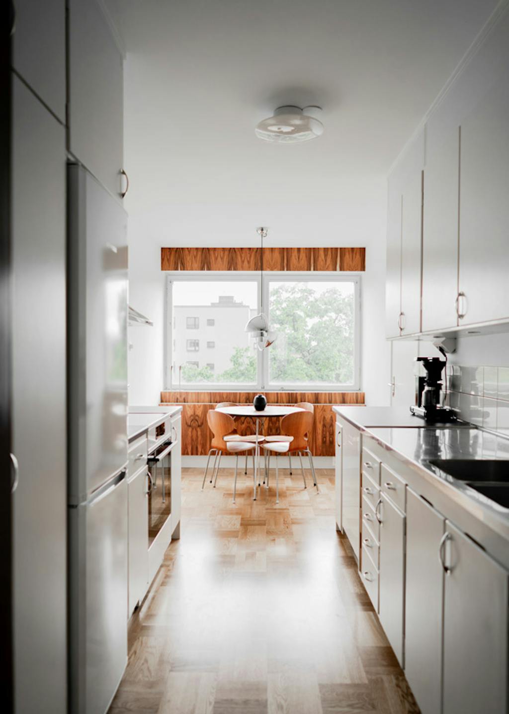 In lijn met de rest van het appartement heeft de keuken zoveel mogelijk zijn jarenzestig look behouden. Jarenzestig stijl keuken met Arne Jacobsen tafel en stoelen
