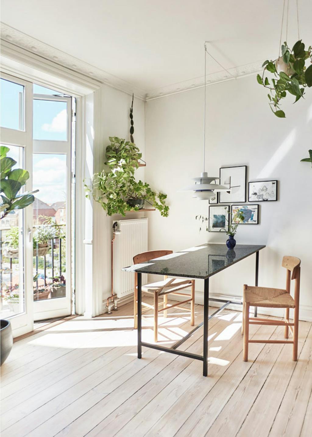 De smalle eettafel van graniet is van Nordal, eromheen staan klassieke J39-stoelen van Børge Mogensen. Boven tafel hangt een discrete PH-lamp.