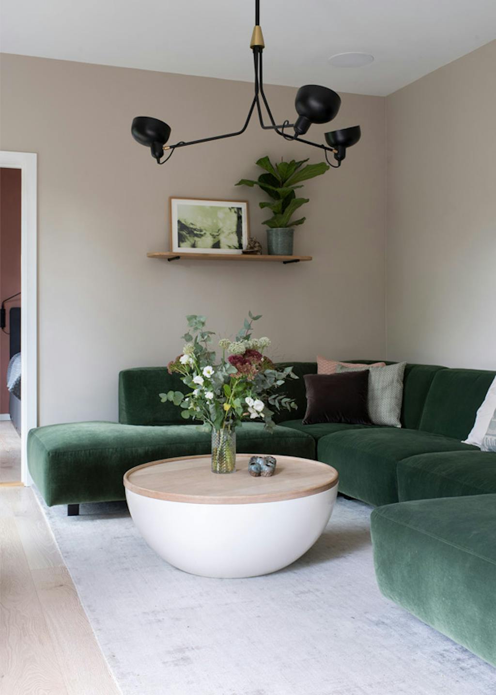 woonkamer met donkergroene bank en beige muur
