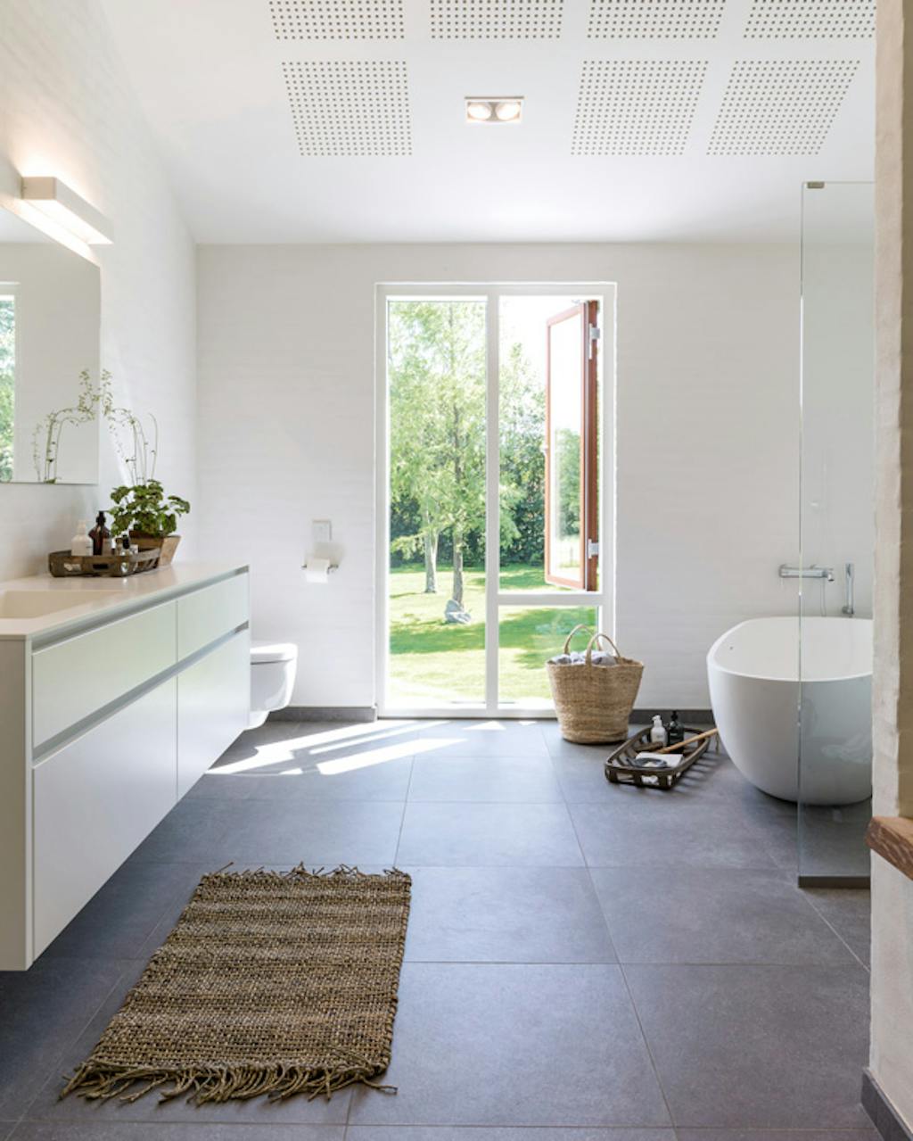 lichte badkamer met donkere tegelvloer en vrijstaand bad