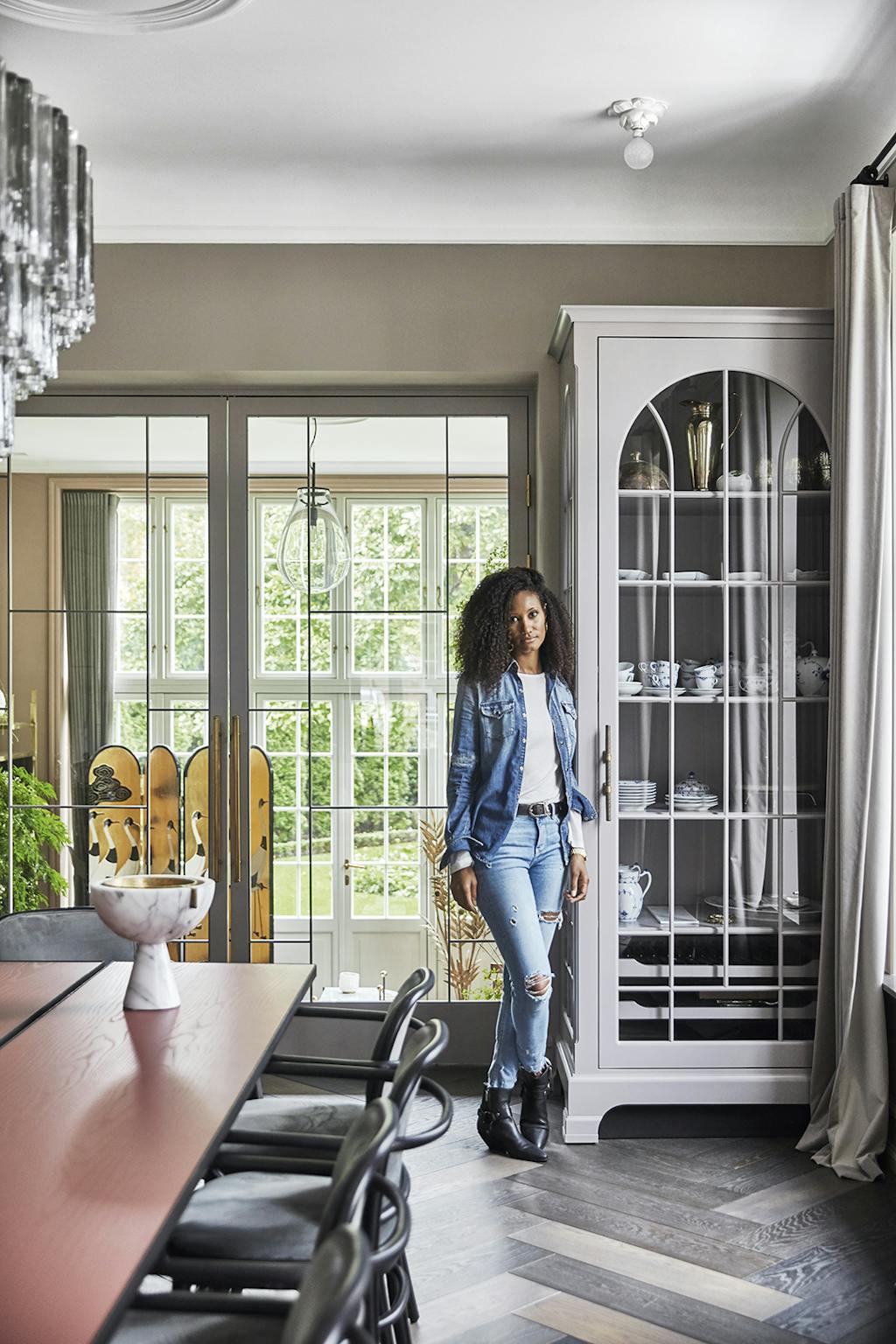 Cora Lucaz in haar prachtige huis met een doorkijkje naar de winterkamer en naast een zelf ontworpen vitrinekast.