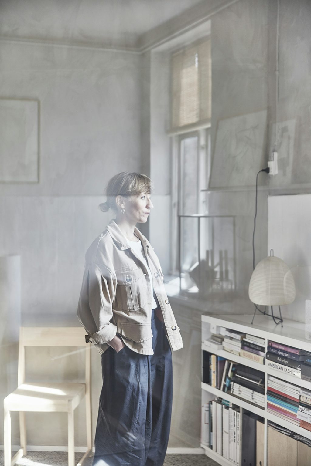 Sara kijkt uit het raam van de Atelier Cph studio. Sara Ingemann in hybride Atelier Cph studio.