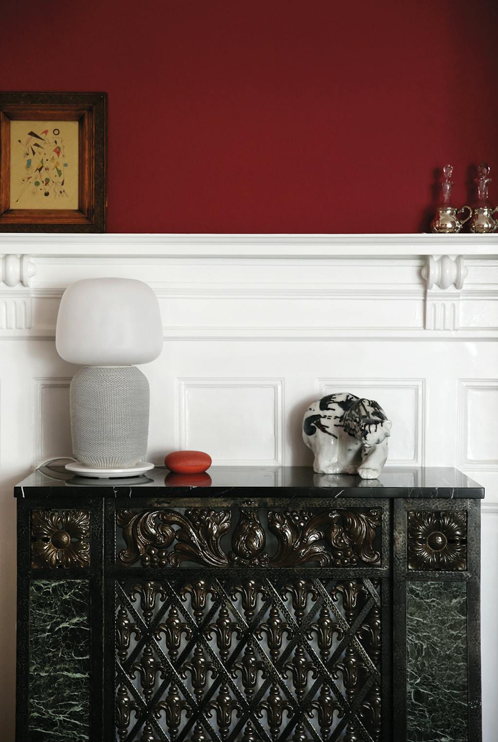 Google Home en Sonos op oude radiatorombouw en rode muur. 