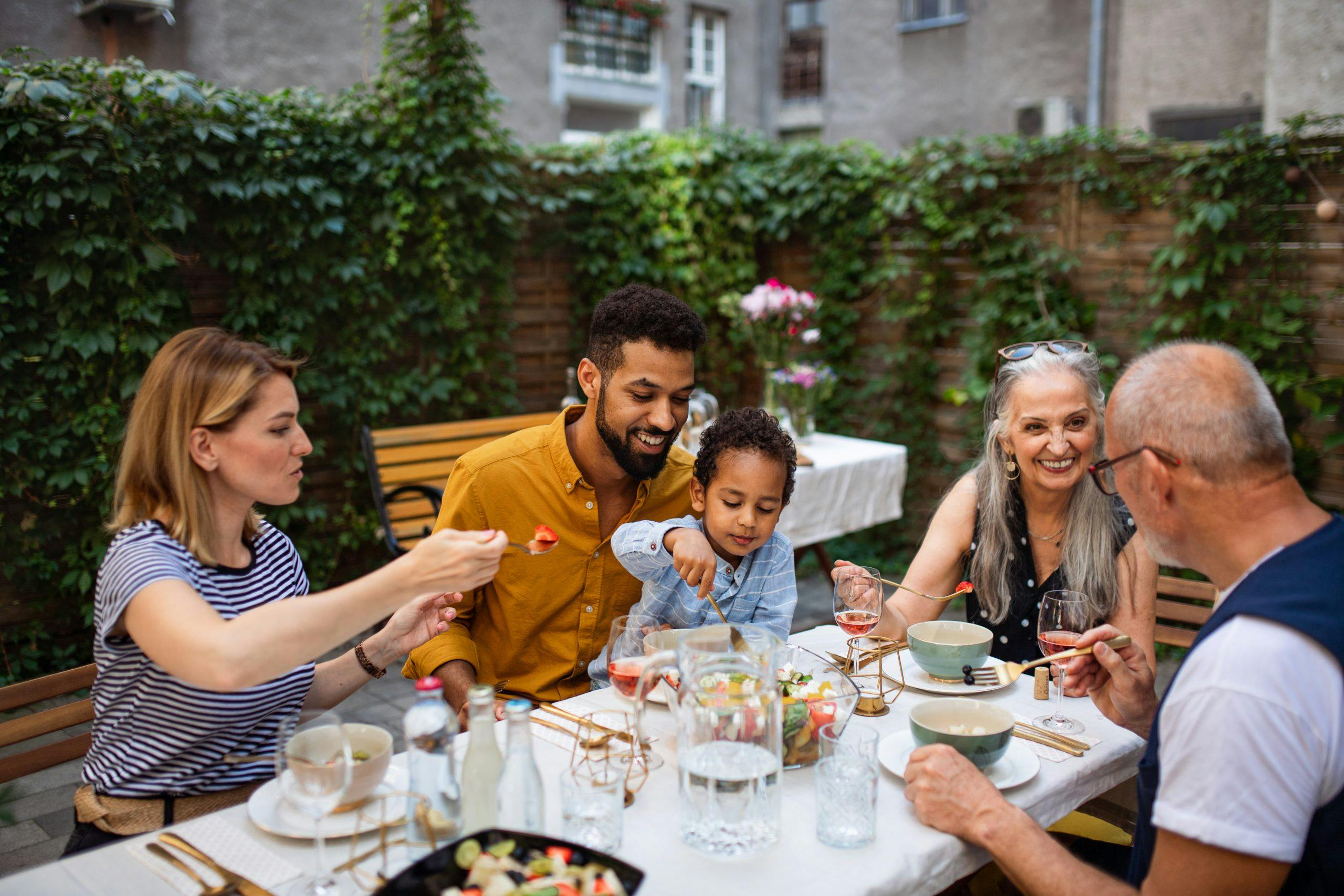 Portrait of multiracial three generations family having dinner together outdoors in front or back yard.