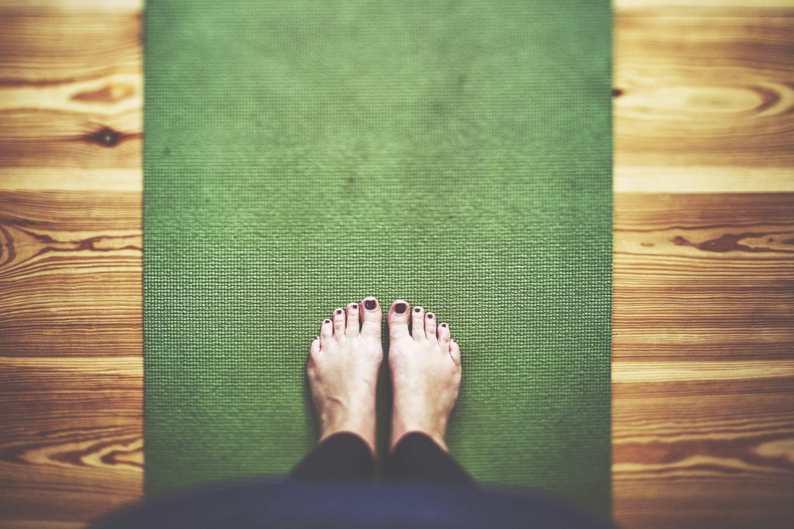 Bare feet on the green Yoga mat