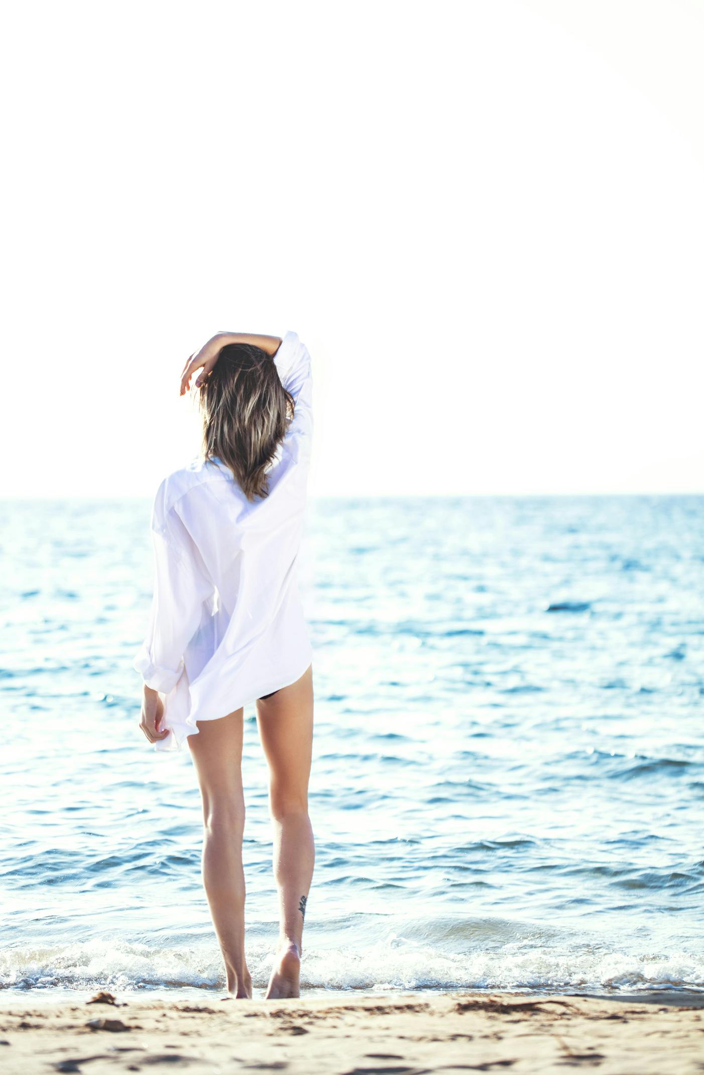 Kvinne på stranden i hvit skjorte
