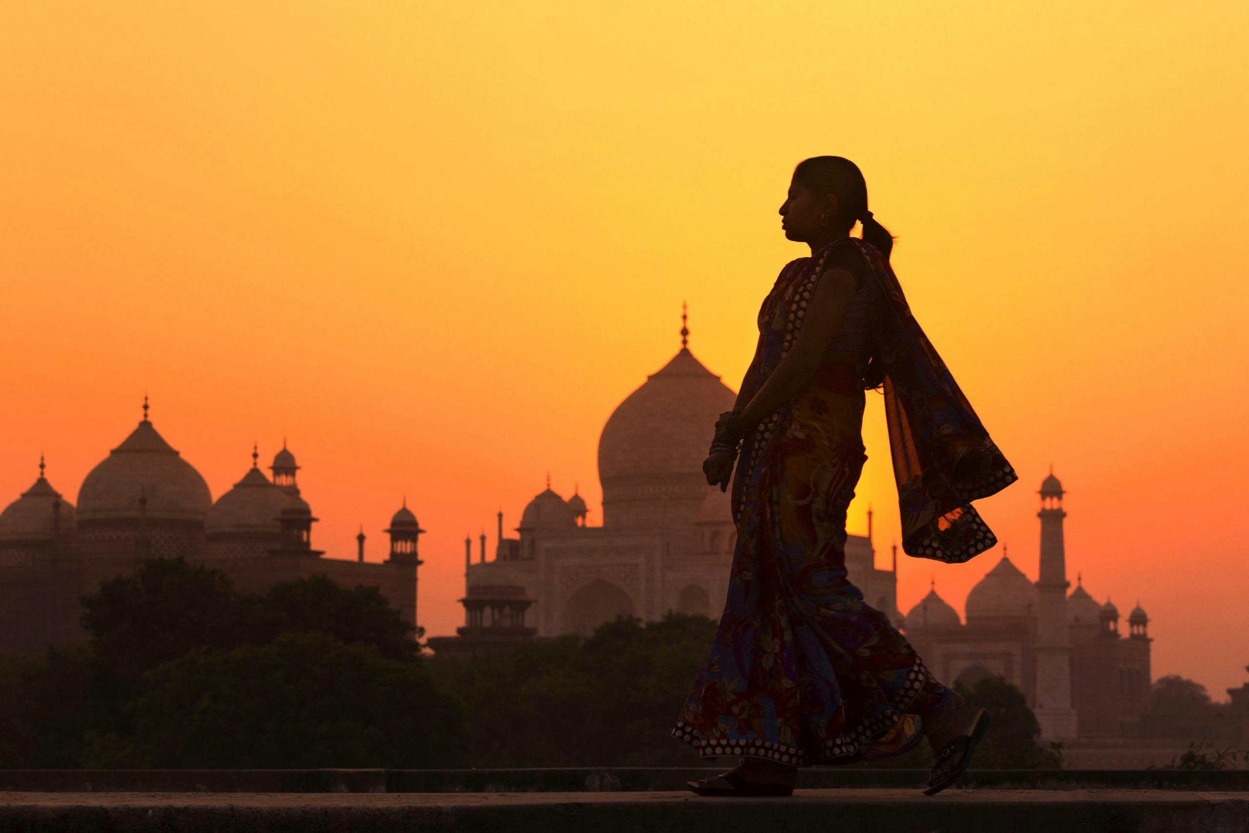 kvinne i solnedgang foran Taj Mahal