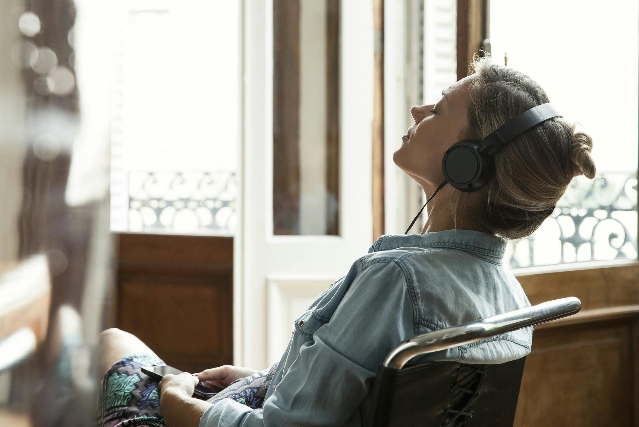 Kvinne med hodetelefoner lytter til podcast