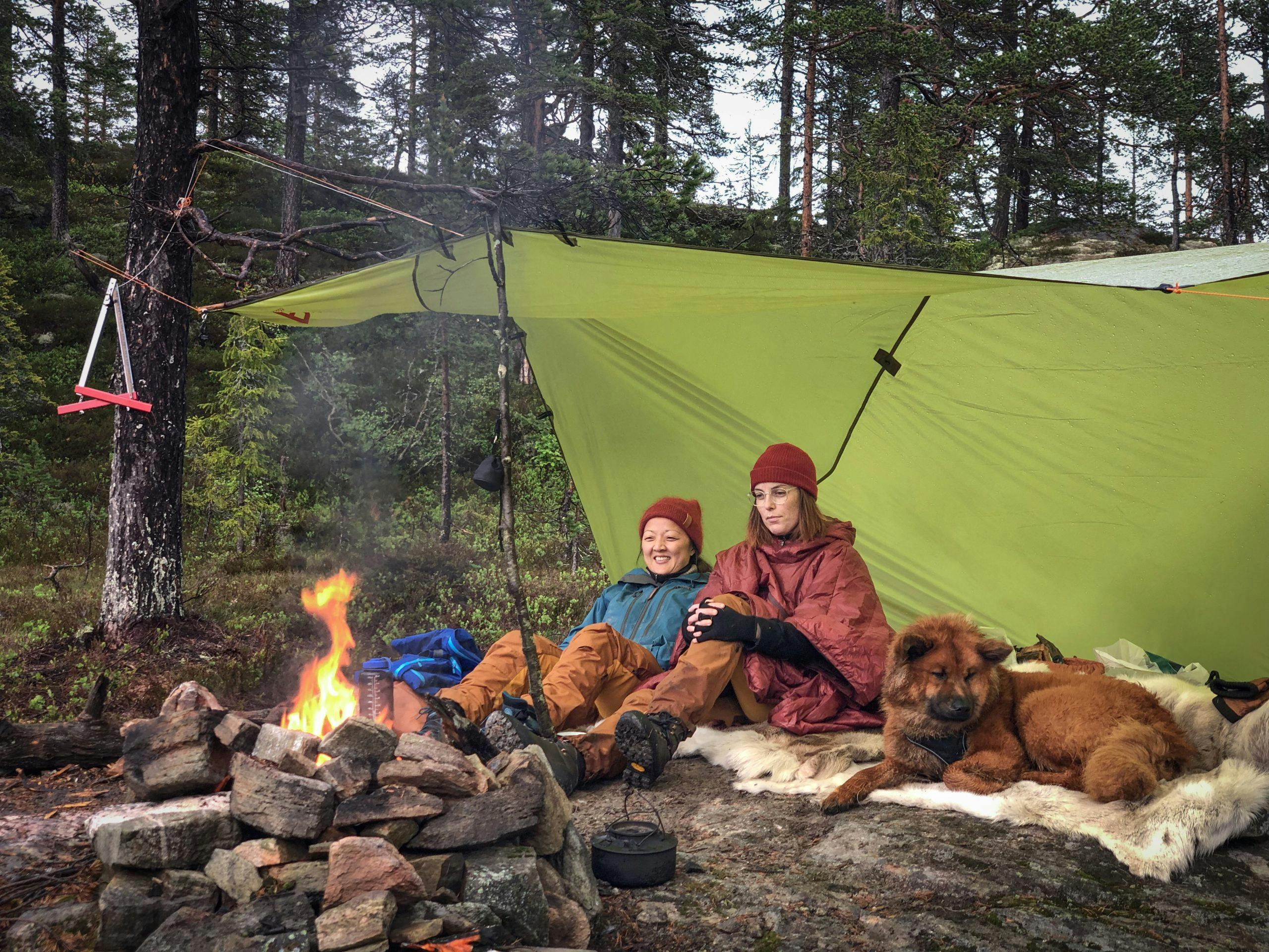 Kvinner som koser seg rundt bålet på fjell-teltturen